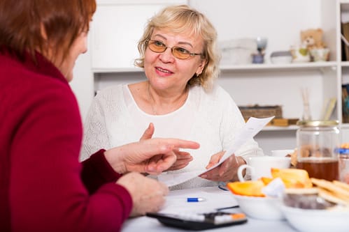 Getting to know people in context Photograph of two women sitting at a kitchen table and talking, illustrating the Social Context approach to human-centred design research.